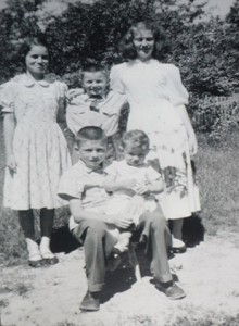A picture of the five of us outside at the Quinn house. I’m thinking this was taken on a Sunday, judging by the fact that I’m wearing my Sunday tie. I’ve got my arms around my big sisters Marjorie and Katharine. Johnny is sitting on a little stool with Leonard on his knees.